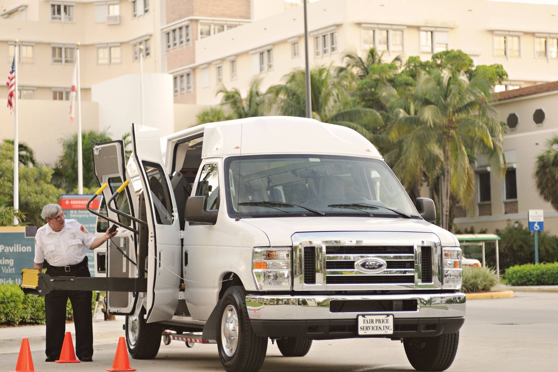 Driver operating a wheelchair lift on an accessible transport van at a medical facility